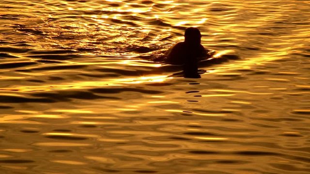 Man swimming at sunset background