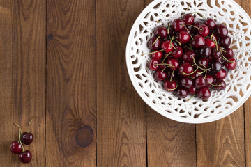 Fototapeta na wymiar Ripe sweet cherry on a laсe bowl. Wooden Background. Flat lay. Top view