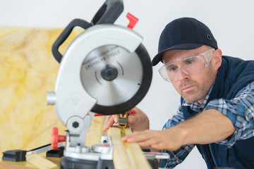Workman using tape measure under circular saw