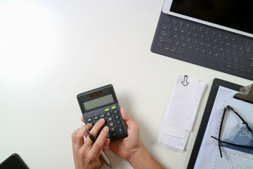 Fototapeta na wymiar top view of businessman hand working with finances about cost and calculator and latop with mobile phone on withe desk in modern office