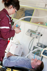 Paramedic preparing oxygen mask to help unconscious man on ambulance stretcher