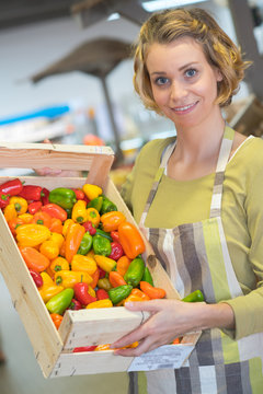 Shop assistant holding crate of peppers