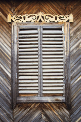 The old weathered wooden closed window with hinges and carved shutters. Retro.