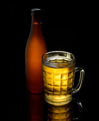 Vintage big beer glass and bottle on a black background