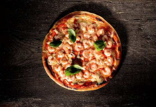 Pizza with shrimps on a wooden background