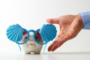 Fototapeta premium Travel insurance concept.business insurance agent hand in gesture of protection of piggy bank with shell sunglasses on white background