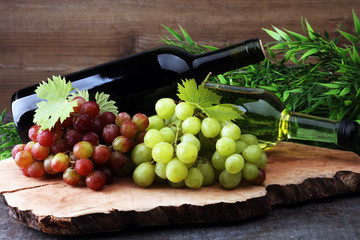 Bottle of white wine, red wine and grape on wooden table
