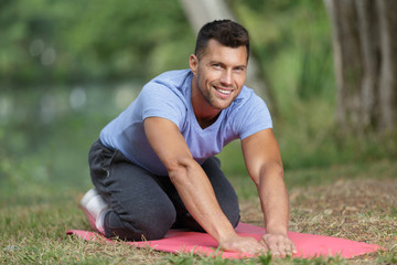 Naklejka na ściany i meble Portrait of man exercising on mat outdoors