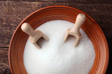 scoop with white sand and lump sugar on brown wooden background