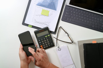 top view of businessman hand working with finances about cost and calculator and latop with mobile phone on withe desk in modern office