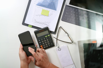 top view of businessman hand working with finances about cost and calculator and latop with mobile phone on withe desk in modern office