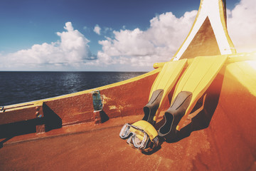 Fototapeta premium Yellow fins and swimming mask laying on bottom of diving boat next to stern on warm sunny summer day with Indian ocean in background and copy space for text, your logo or advertising message