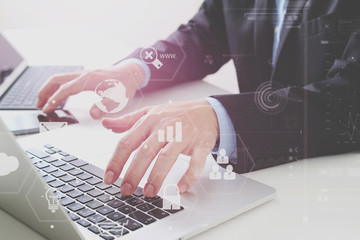 Hands of businessman typing on laptop in modern office with smart phone and digital tablet computer