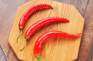 Three red hot peppers on the cutting board
