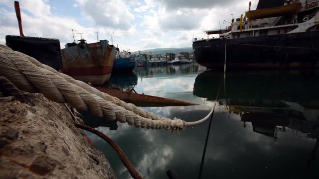 Sea Port. Ships Staying in Bay. Old Fish Boat in Dock. Rope Hanging. Rust Metal. Cloudy Sky Reflection on Water. Summer Day