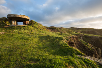 Fototapeta na wymiar Bunker in sunny grassland on rocky coast