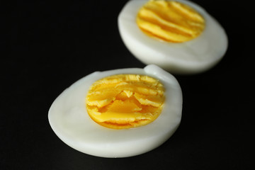 Sliced hard boiled egg on black background. Nutrition concept