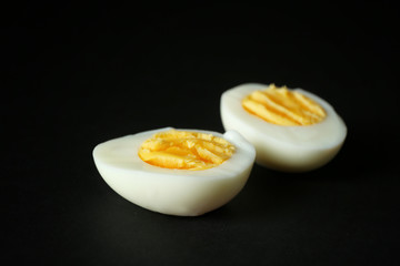 Sliced hard boiled egg on black background. Nutrition concept