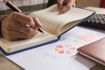 Businessman check seriously analyzes a financial reports and writing on notebook on wooden table at office ,Finance managers task,Concept business and finance