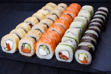 Gordijnen Colorful delicious set of sushi served on  black slate, close up. Japanese cuisine, restaurant menu photo. © Vadym