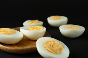 Wooden tray and hard boiled eggs on black background. Nutrition concept