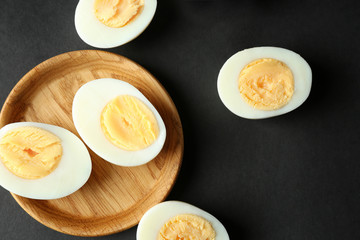 Wooden tray and hard boiled eggs on black background. Nutrition concept