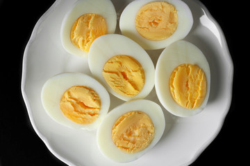 White ceramic plate with hard boiled eggs on black background. Nutrition concept