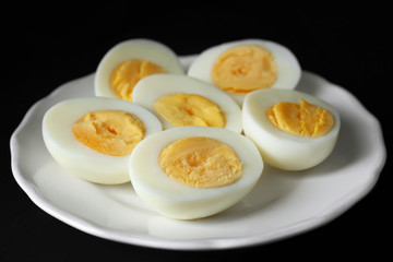 White ceramic plate with hard boiled eggs on black background. Nutrition concept