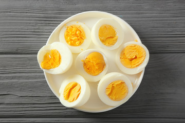 Ceramic tray with sliced hard boiled eggs on wooden table. Nutrition concept