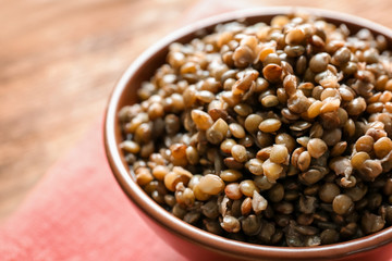 Bowl with tasty lentil porridge on table, closeup