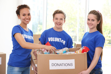 Young volunteers with box of donations indoors