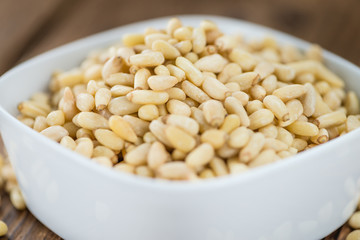 Portion of Pine Nuts on wooden background (selective focus)