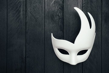 White carnival mask on black wooden wall. Swan. Empty space.