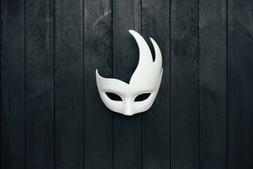 White mask on black wooden wall. Swan. Copy space.