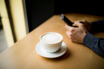 Man typing a sms on phone while drink a cup of coffee