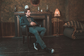  Portrait of a businessman who sits by the fireplace with a pensive look