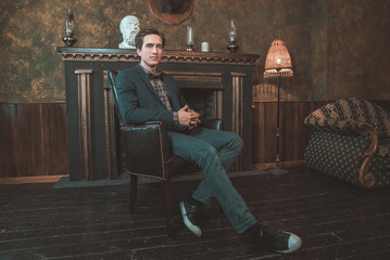 Portrait of a business man who sits by the fireplace with a thoughtful look...