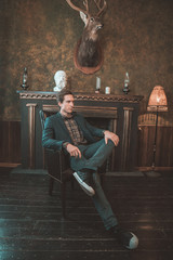 Portrait of a business man who sits by the fireplace with a thoughtful look...