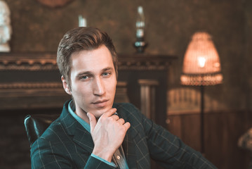 Portrait of a business man who sits by the fireplace with a thoughtful look...