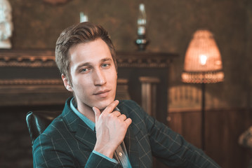 Portrait of a business man who sits by the fireplace with a thoughtful look...