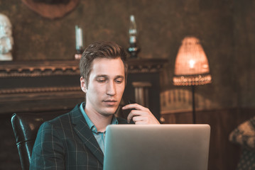 Man with computer sitting by the fireplace and talking on the phone