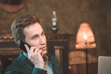 Man with computer sitting by the fireplace and talking on the phone
