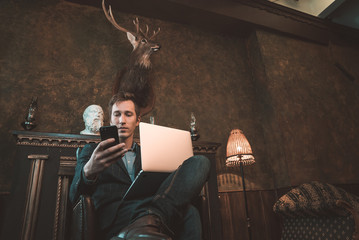 Man with computer sitting by the fireplace and talking on the phone