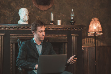 Man with computer sitting by the fireplace and talking on the phone