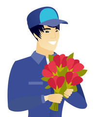 Young asian mechanic holding a bouquet of flowers