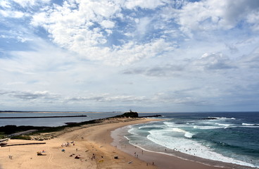 Fototapeta na wymiar Beach at Newcastle. Nobbley's Lighthouse in the background.