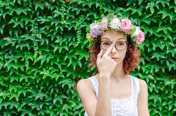Fototapeta premium woman with wreath on head raises eye glasses