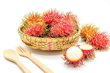 Fototapeta na wymiar fresh tropical rambutan fruits over basket with spoon and fork on a white background, fruit in Thailand