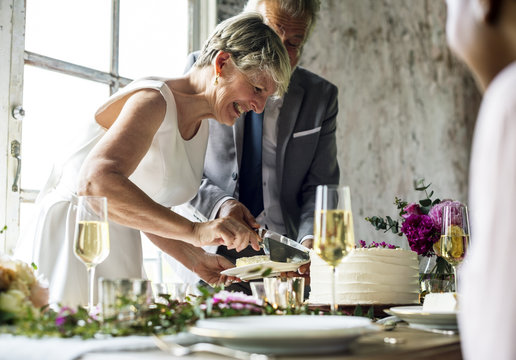 Senior Couple Hands Cutting Wedding Cake
