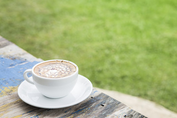 Hot coffee on wood with blur background.